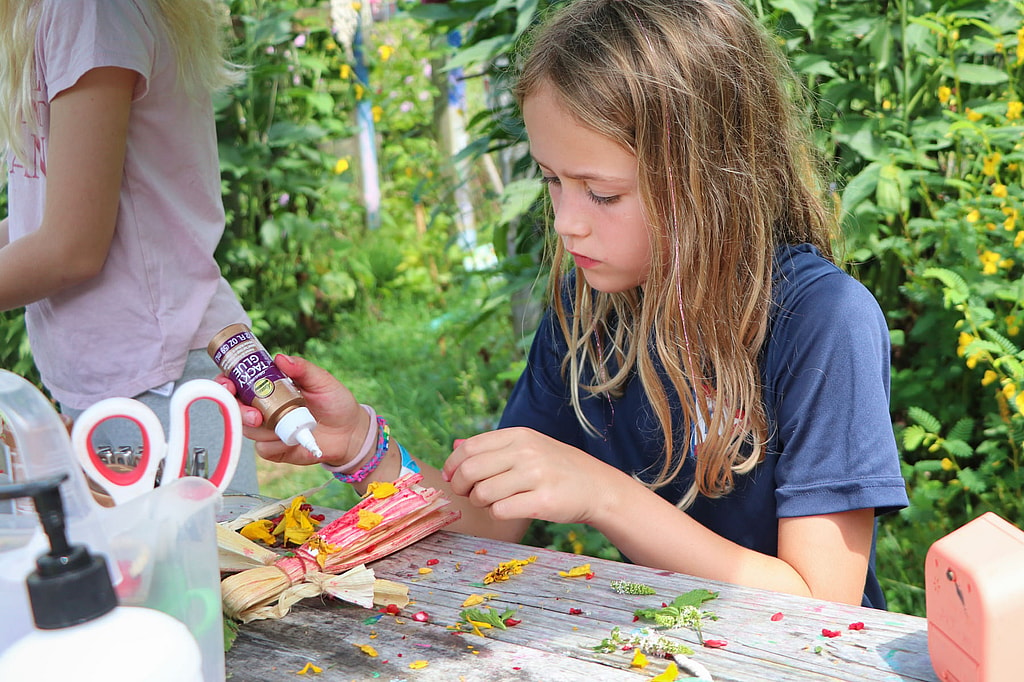 camp girl making corn husk doll